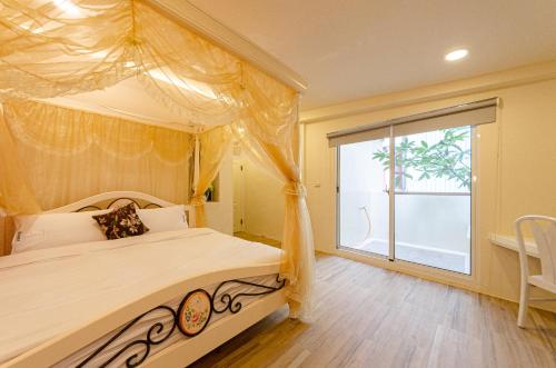 埔里鎮的住宿－埔里歐亞包棟民宿，一间卧室设有一张天蓬床和大窗户