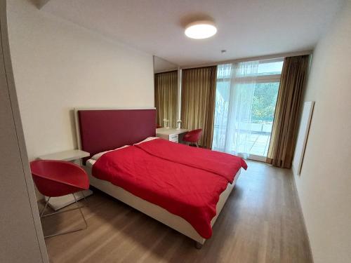 una camera con un letto rosso e una grande finestra di LB2 Seeappartement Haus Landskron direkt am Ossiachersee a Landskron