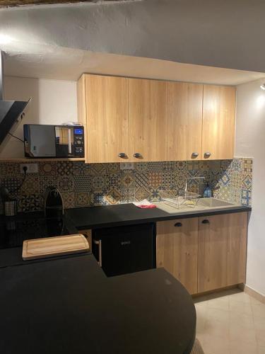 une cuisine avec des armoires en bois et un comptoir noir dans l'établissement La tour 3: Appart au cœur de la petite Venise, à LʼIsle-sur-la-Sorgue