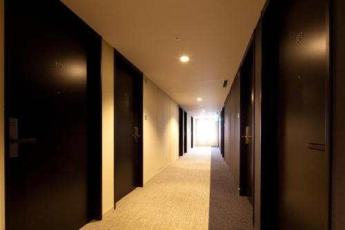 an empty hallway with black doors and a hallway with a hallwayngth at Daiwa Roynet Hotel Tokyo Akabane in Tokyo
