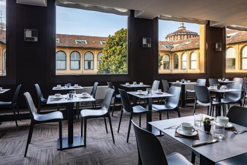 a restaurant with tables and chairs and large windows at Hotel Palazzo Delle Stelline in Milan