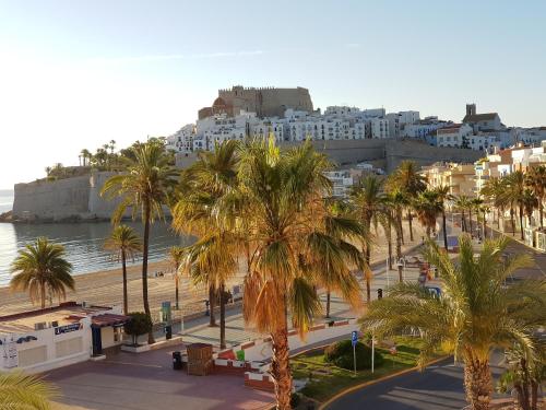 a view of a beach with palm trees and buildings at La Cabaña in Peñíscola
