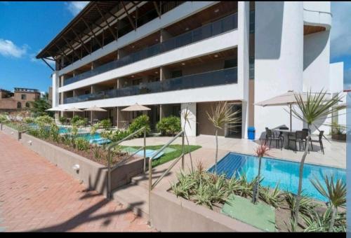 a large building with a pool and tables and chairs at Porto Central Residence 01 in Porto De Galinhas