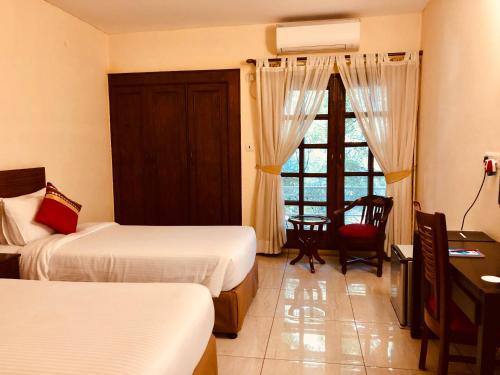 a bedroom with two beds and a desk and a window at The Neem in New Delhi