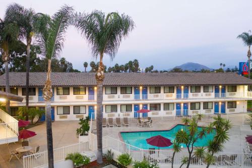 a view of a hotel with a pool and palm trees at Motel 6-Camarillo, CA in Camarillo
