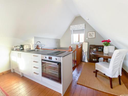 a kitchen with a stove and a table with a chair at Little Dene Lodge in Pakenham