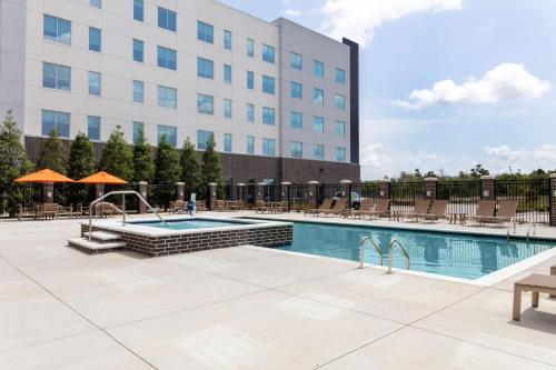 a pool at a hotel with chairs and a building at Hyatt House The Woodlands-Shenandoah in Shenandoah