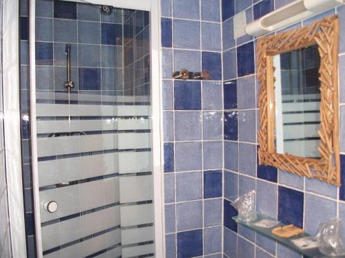 a blue tiled bathroom with a shower and a mirror at Hotel François 1Er in Manosque