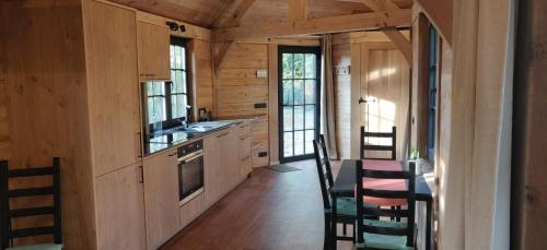 - une cuisine avec des placards en bois, une table et des chaises dans l'établissement Chalet Duras, à Saint-Trond