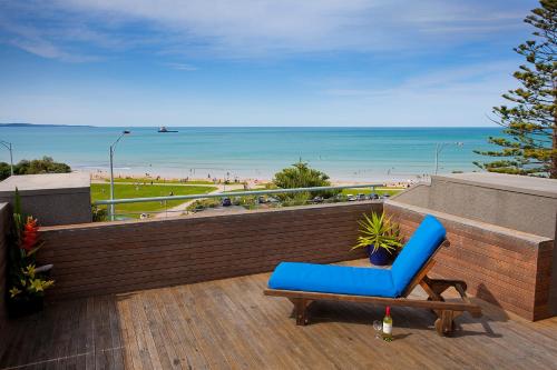 
a blue chair sitting on top of a wooden deck next to a beach at Cumberland Lorne Resort in Lorne
