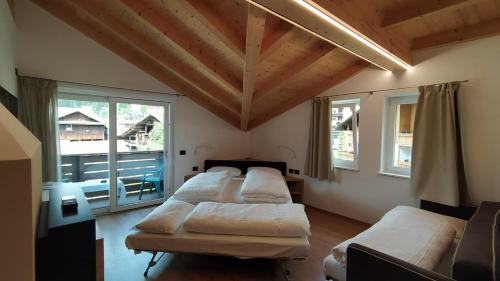 a room with four beds in a room with windows at Hotel Villa Rosa in Campitello di Fassa