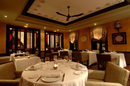 a restaurant with white tables and chairs and a clock on the ceiling at Le Riad Villa Blanche in Agadir