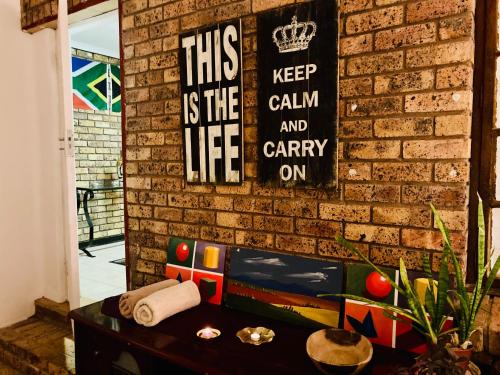 a brick wall with a sign that reads this keep calm and carry on at Su Casa Chase Valley VA in Pietermaritzburg
