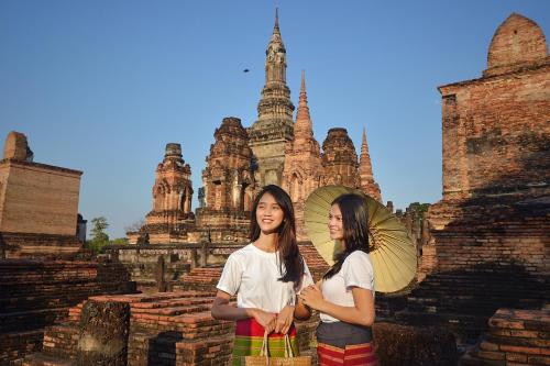 two young people standing in front of a building with an umbrella at Thai Thai Sukhothai Resort in Sukhothai