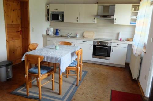 y cocina con mesa, sillas y fogones. en Haus Alpaka, en Bad König