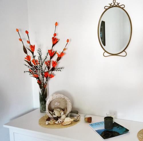 a table with a vase with flowers and a mirror at Eden Apartment in Anacapri