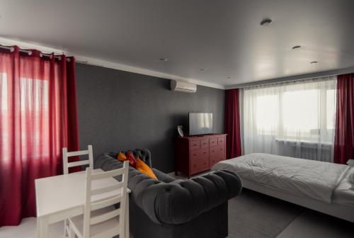 a bedroom with a couch and a bed with red curtains at Назарбаева209/17 in Uralsk