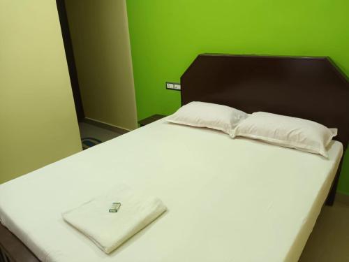 a white bed with a wooden headboard and a white pillow at isha homestay in Varkala