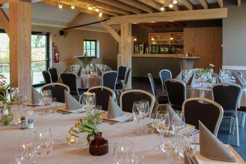 een kamer met lange tafels en stoelen met wijnglazen bij Bouwelhoeve 't Schuur in Grobbendonk