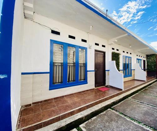 un edificio blanco con puertas y escaleras azules en Kalih Homestay, en Pagaralam