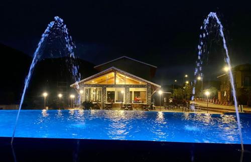 a large swimming pool with fountain in front of a building at Mastiff Grand La Villae in Lonavala