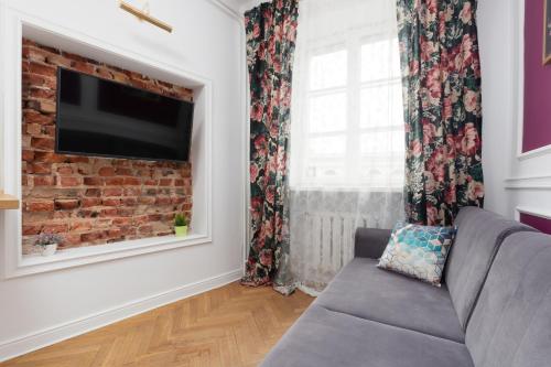 a living room with a couch and a brick wall at Apartament przy Placu Zamkowym by Renters in Warsaw