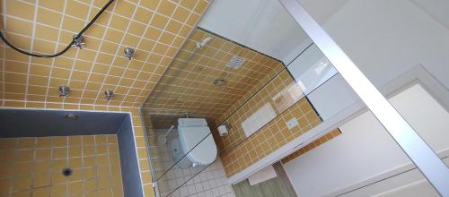 uma casa de banho em azulejos amarelos com um WC e um espelho. em Maison de L'ocean Praia 250 m em Florianópolis