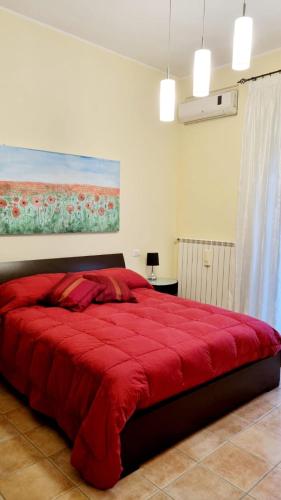 a bedroom with a red bed with a painting on the wall at Civico 64 in Ortona