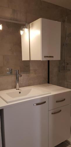 une salle de bain avec un lavabo blanc et un miroir dans l'établissement Le Narval-appartement 5, à Calcatoggio