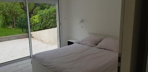une chambre avec un lit et une grande fenêtre dans l'établissement Le Narval-appartement 5, à Calcatoggio