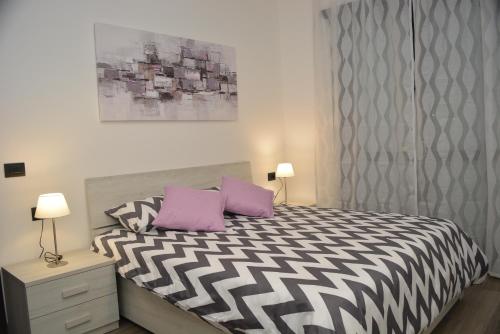 Un dormitorio con una cama en blanco y negro con almohadas moradas en Ginevra Home, en Sesto San Giovanni