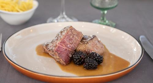 a plate of food with meat and blackberries on a table at Hotel Don Curro in Málaga