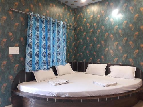 Ce lit se trouve dans une chambre dotée d'un mur recouvert de papier peint. dans l'établissement Hotel RAJVIHAR, à Pachmarhī