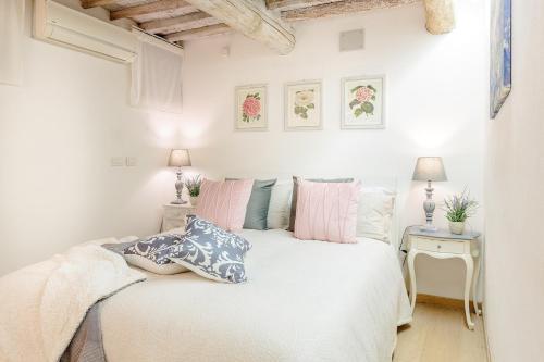 a bedroom with a white bed with pink and blue pillows at Orchidea Bianca, a 2 Bedrooms 2 Bathrooms Understated Luxury with a Welcoming Ambience in Lucca