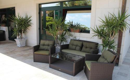 a patio with two couches and a table and plants at Apartments Logos in Cavtat