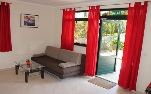 - un salon avec un canapé et des rideaux rouges dans l'établissement Apartments Logos, à Cavtat