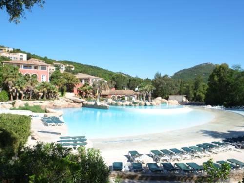 a large swimming pool with chairs and a beach at Les Restanques coquelicot vue mer in Grimaud