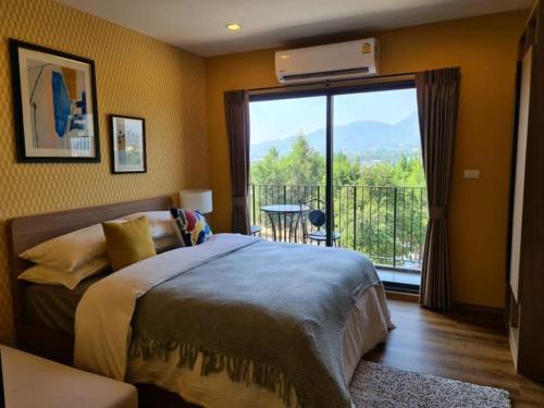 een slaapkamer met een bed en een groot raam met een balkon bij Huahin mountain view room near the beach in Hua Hin