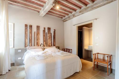 a bedroom with a white bed and two chairs at Palazzo Giusti, Understated Luxury with a Welcoming Ambience on the Hills of Lucca in Pescaglia