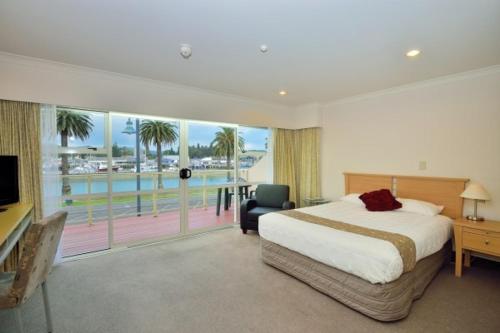 a bedroom with a bed and a view of the ocean at Senator Motor Inn in Gisborne