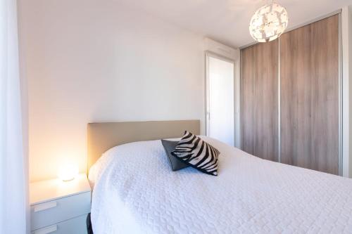 une chambre avec un lit blanc avec un oreiller dessus dans l'établissement Renovated 2-Br Apartment with Terrace and Pool, à Cannes