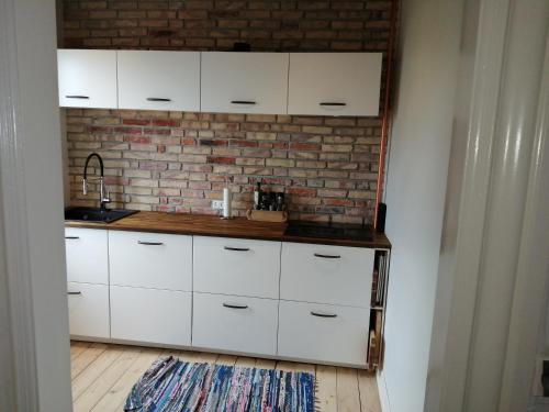 una cocina con armarios blancos y una pared de ladrillo en Cozy Villa-Apartment - Close to Aalborg center - Free citybikes and parking, en Aalborg