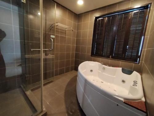 a bathroom with a shower and a tub and a sink at Buluh Inn @ Gold Coast Morib in Banting