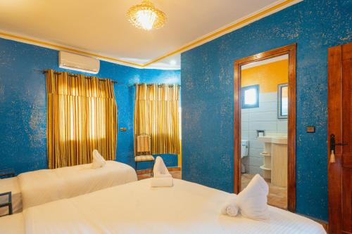 a blue room with two beds and a bathroom at Kasbah Hotel Ziz Palace Rissani in Rissani
