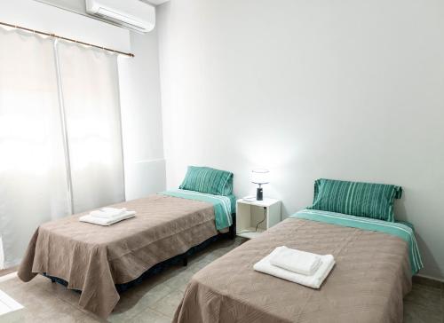two beds in a white room with towels on them at Departamento Moreno 2 in Santa Rosa