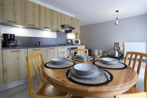 - une table en bois avec des bols et des assiettes dans la cuisine dans l'établissement Le Jardin de Boubioz, à Sévrier