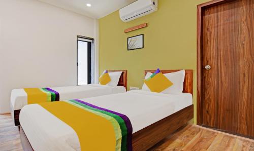 two beds in a room with yellow walls at Itsy Hotels Shivshakti in Aurangabad