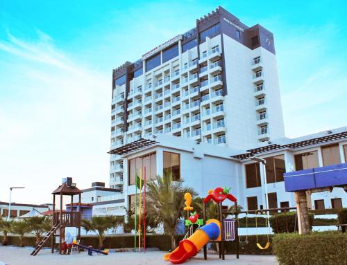 Mirage Bab Al Bahr Beach Resort في دبا: مبنى كبير فيه ملعب امام مبنى