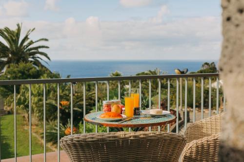 una mesa con comida y zumo de naranja en un balcón en Moinho das Feteiras, en Feteiras
