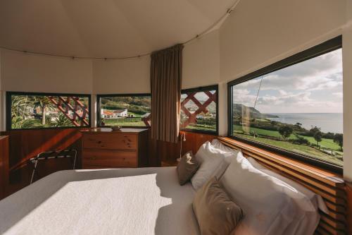 a bedroom with a bed and two large windows at Moinho das Feteiras in Feteiras